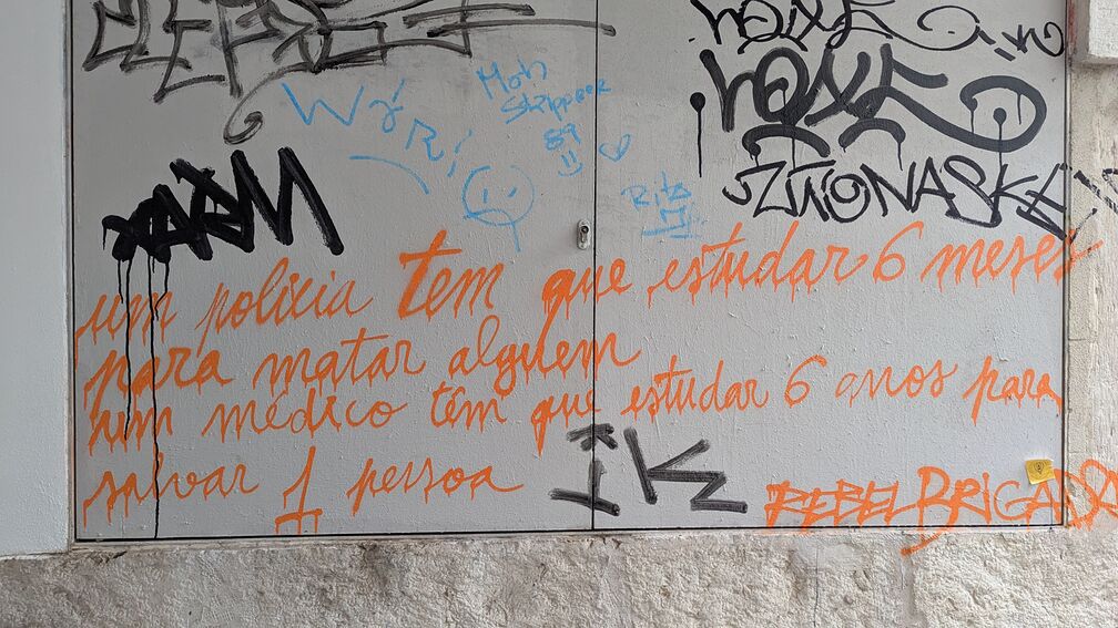 Spray painted graffiti photographed in Lisbon. It's in Portugese, but a rough English translation is: 'A police officer has to study 6 months to kill somebody, a doctor has to study 6 years to save 1 person'. click for full resolution.