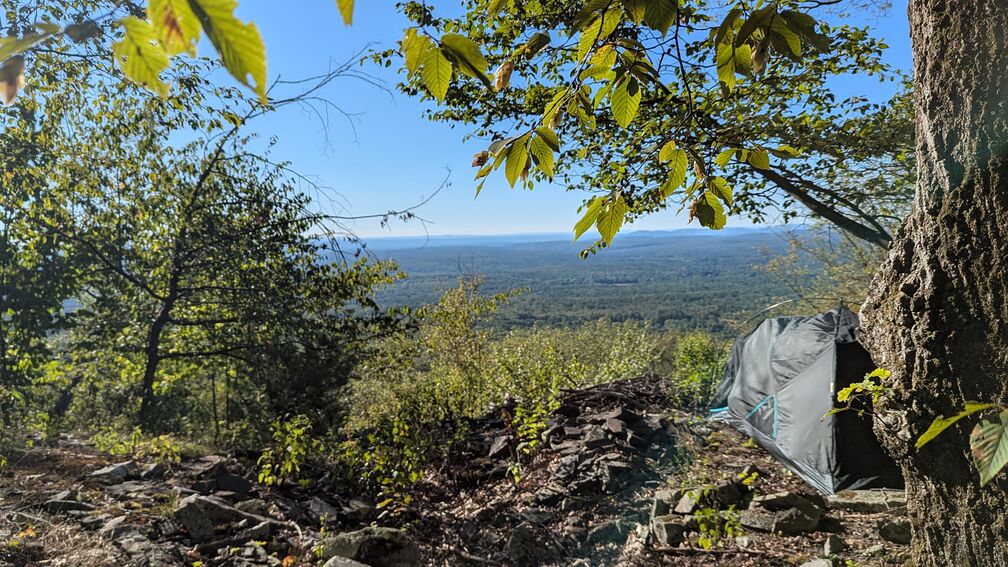 A tent at the edge of a bluff overlooking a seemingly endless forest click for full resolution.