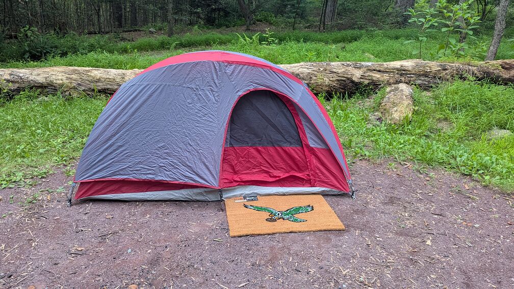 A tent at a campsite with a Philadelphia Eagles welcome mat placed in front of the entrance click for full resolution.