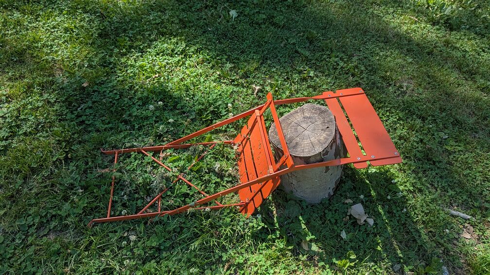 An orange folding chair placed over top a wooden stump. A bit redundant really. click for full resolution.