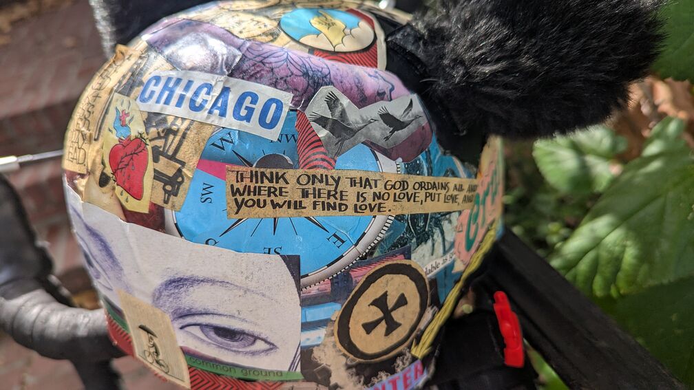 a bike helmet with a crazy cool collage papered on it. prominent text reads: Think only that God ordains all and where there is no love, put love, and you will find love. Another sticker says: Chicago. click for full resolution.