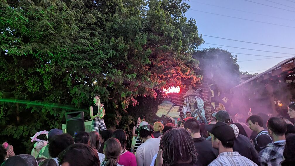 A photo from a Mariposas Galacticas concert I went to at Philly Porchfest. One of the band members plays her saxophone triumphantly. click for full resolution.