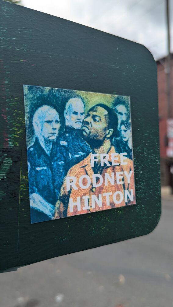 A sticker with Rodney Hinton being surrounded by white cops. Text reads: Free Rodney Hinton click for full resolution.