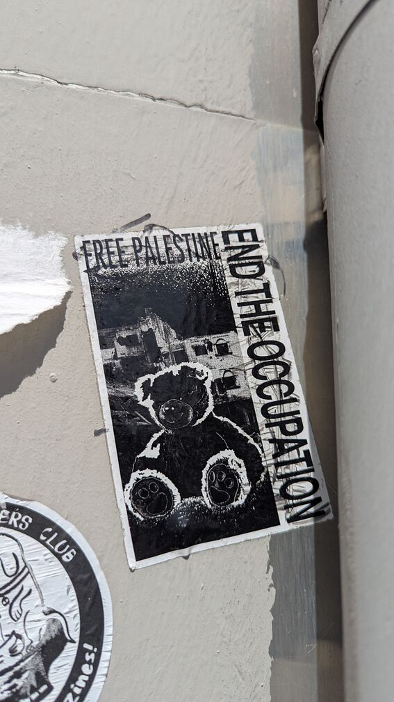 A black and white digital collage of a teddy bear in front of blown up buildings. Text reads "Free Palestine. End the occupation." click for full resolution.