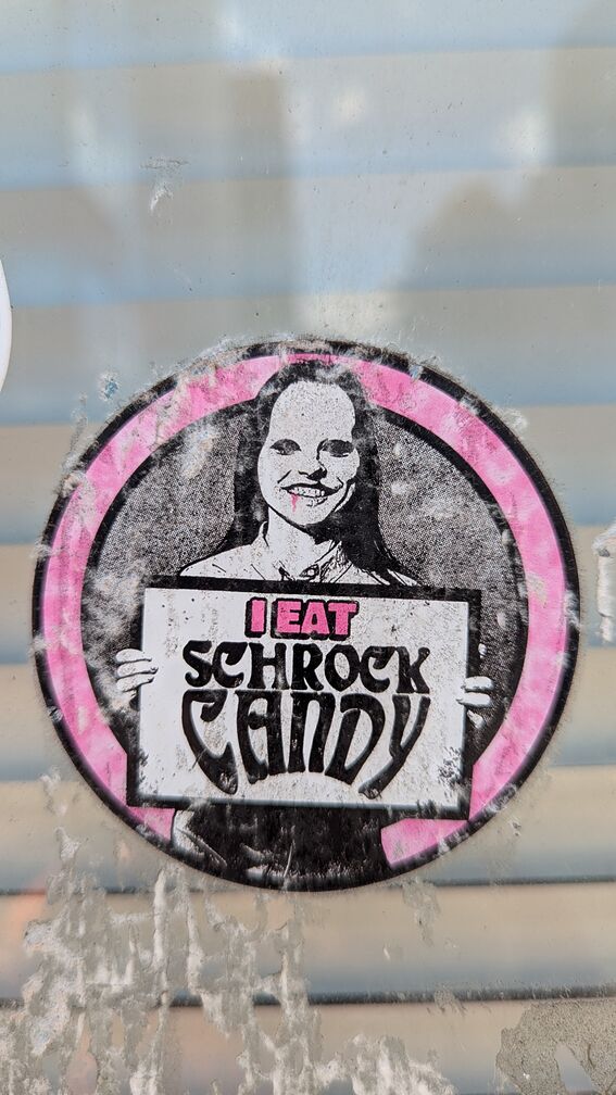 A sticker of a creepy woman with blood dripping from her mouth holding a sign that says: I eat Shrock Candy click for full resolution.