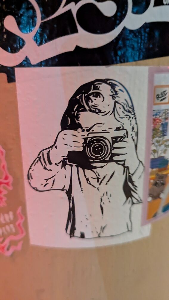 An illustration of a child taking a photo with an camera. The camera completely blocks out their face. click for full resolution.