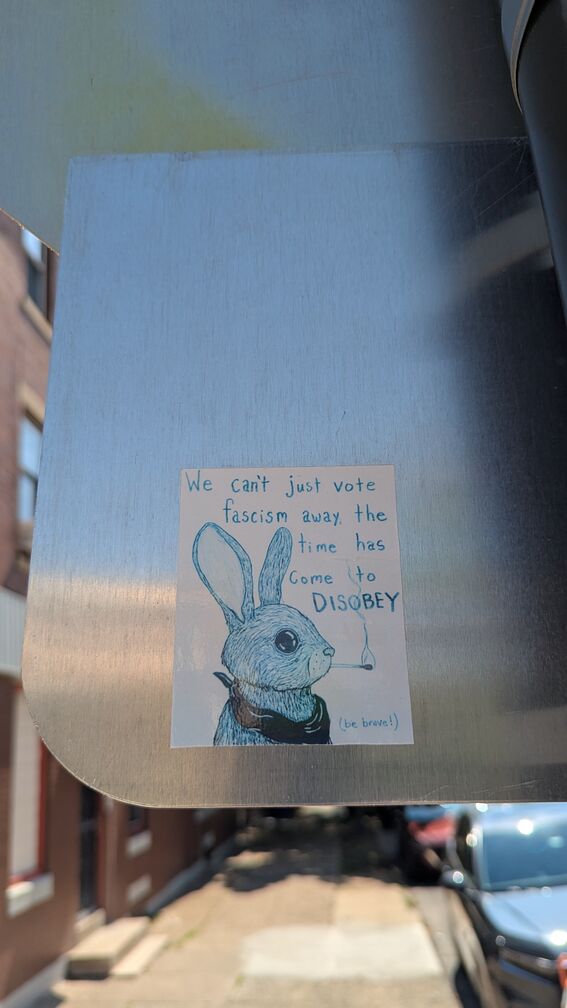 A sticker with a handrawn rabbit figure smoking a cigarette. Text reads: We can't just vote facism away, the time has come to disobey. (be brave!) click for full resolution.
