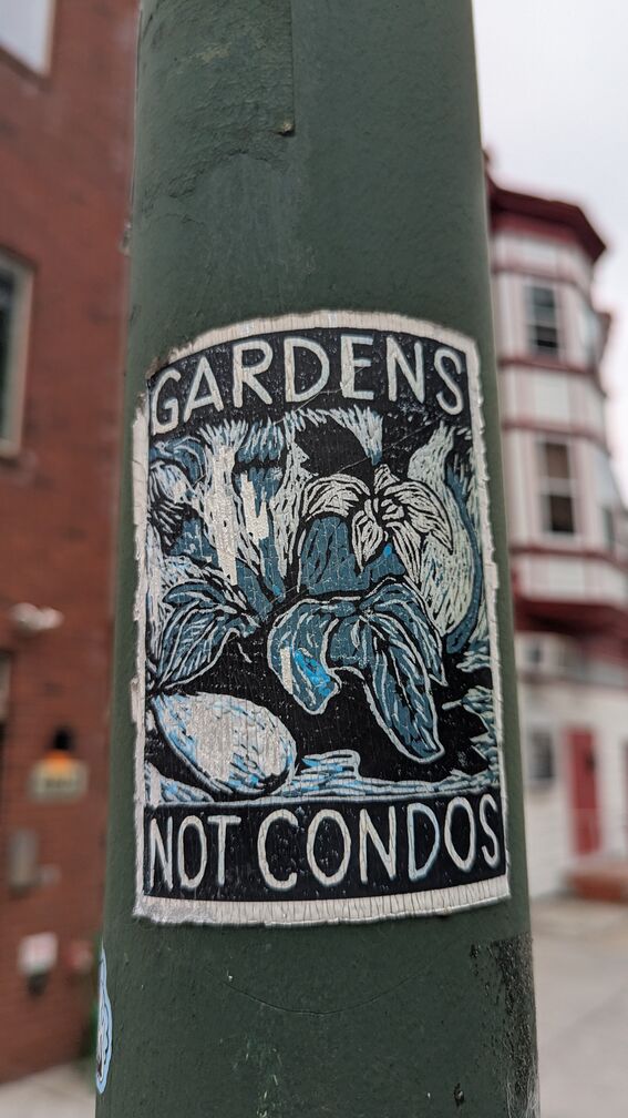 A sticker with a blockprint of tropical plants and text that reads: Gardens Not Condos click for full resolution.