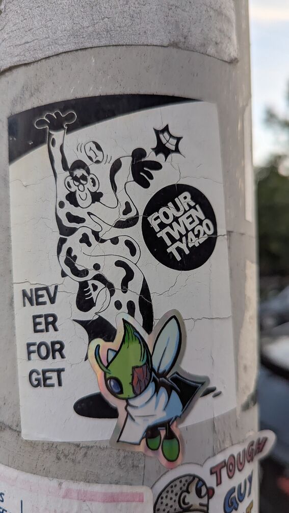 A cartoon of a strange mime, with the text FourTwenty420 and Never Forget on it. There's also a sticker of a scarred Celebi Pokemon slapped on top of it. click for full resolution.