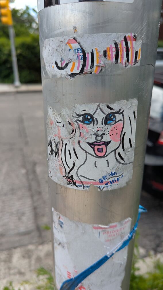 A flaking away sticker, drawn in marker, featuring a woman with anime eyes and a septum piercing dissolving a tab on her tongue. There's an Instagram handle, but it's been worn away by the elements click for full resolution.
