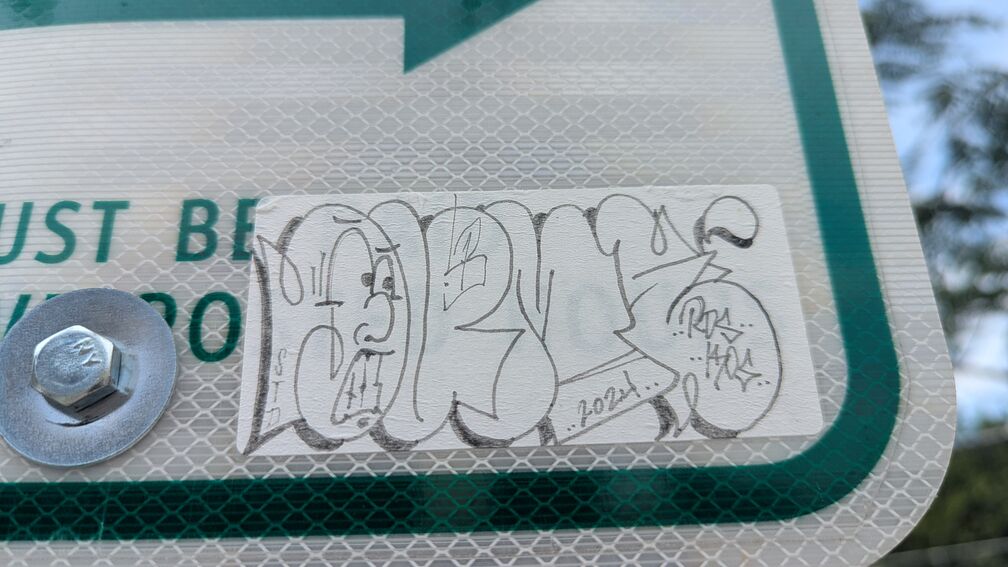 A bubble art grafitti slap from 2024. The first letter has a face drawn into it. click for full resolution.