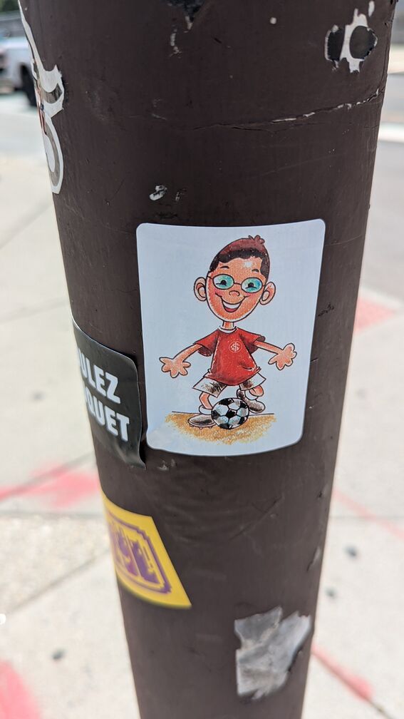 A drawing of a little bespectacled kid in a red jersey kicking a soccer ball click for full resolution.