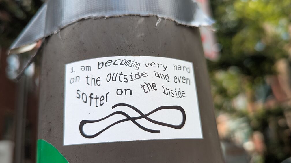 A curly sticker that reads: i am becoming very hard on the outside and even softer on the inside click for full resolution.